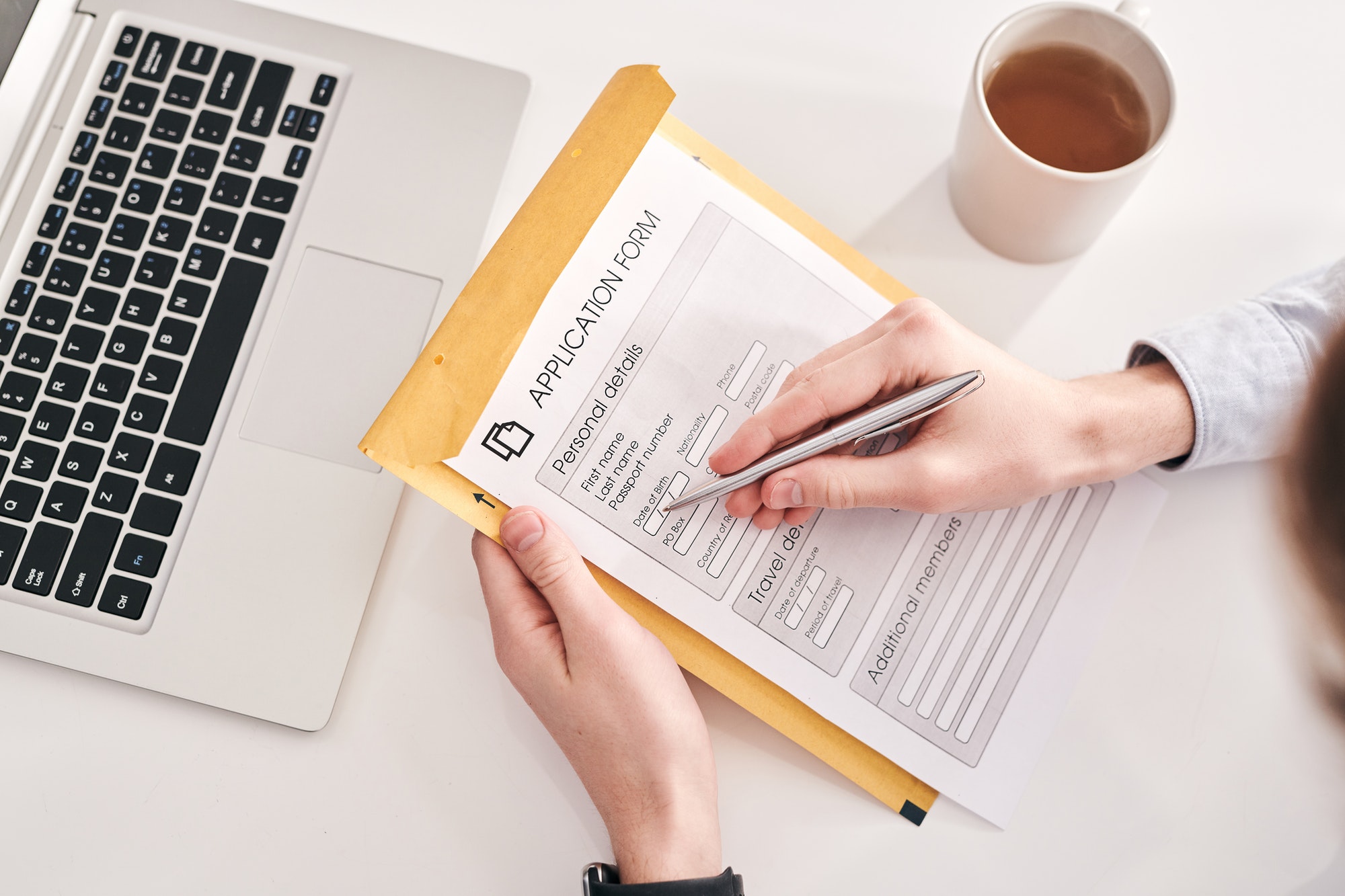 Person filling out a job application form with a pen