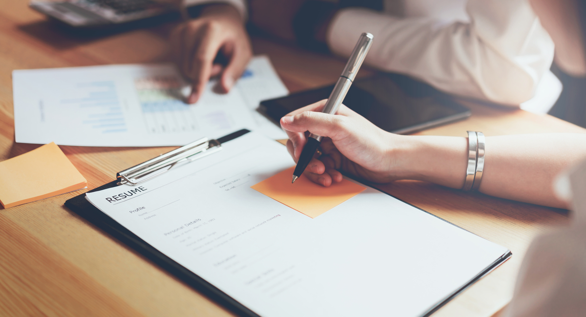 Hand writing on a resume document with a pen