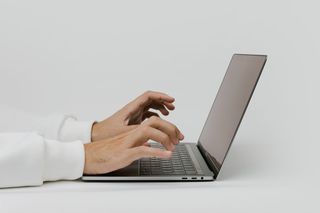 Hands typing on a laptop while drafting a resume