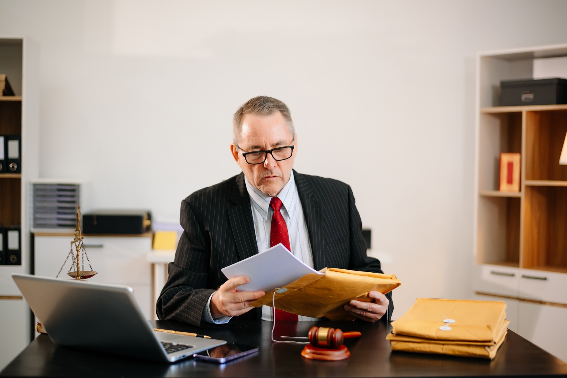 Legal professional reviewing documents at a desk with gavel and scales of justice